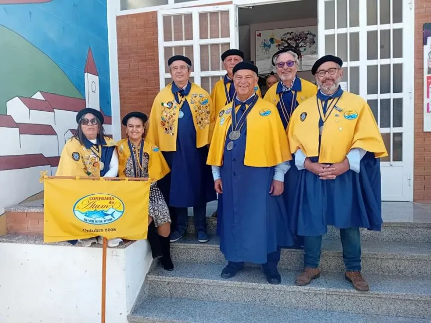 Grupo em trajes tradicionais com bandeira da confraria.