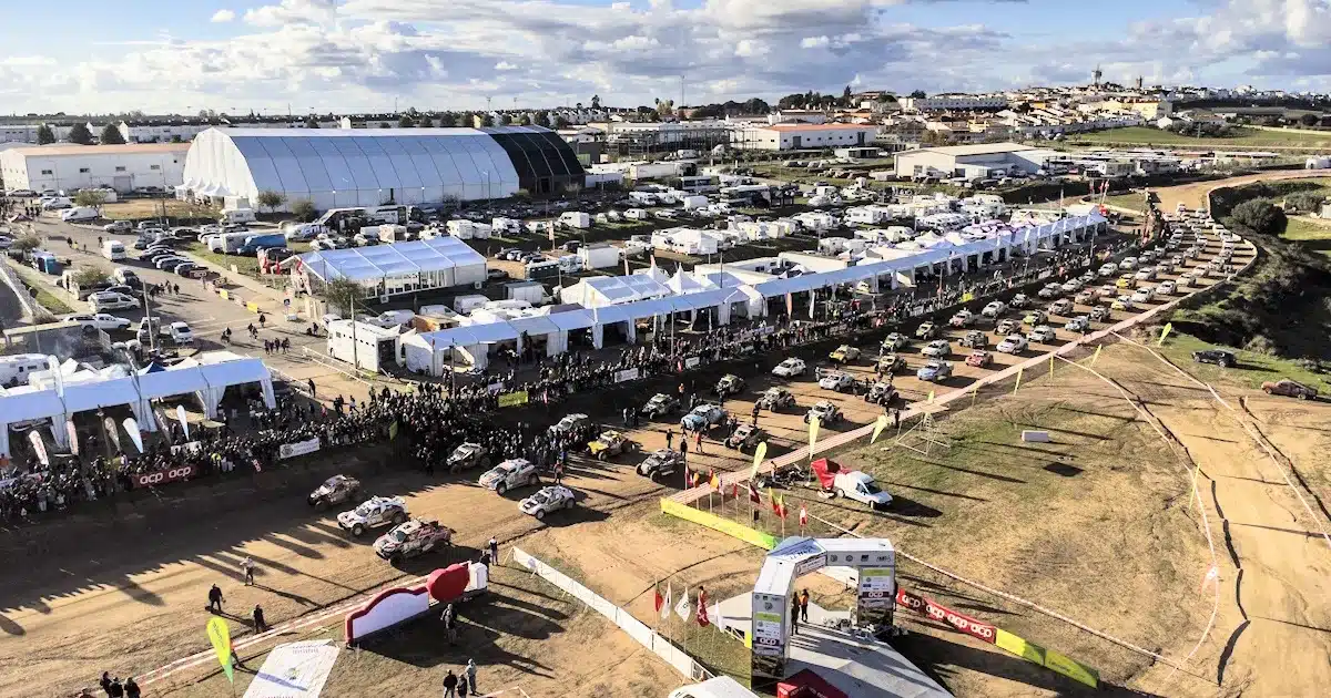 Vista aérea de feira ao ar livre com tendas e carros.