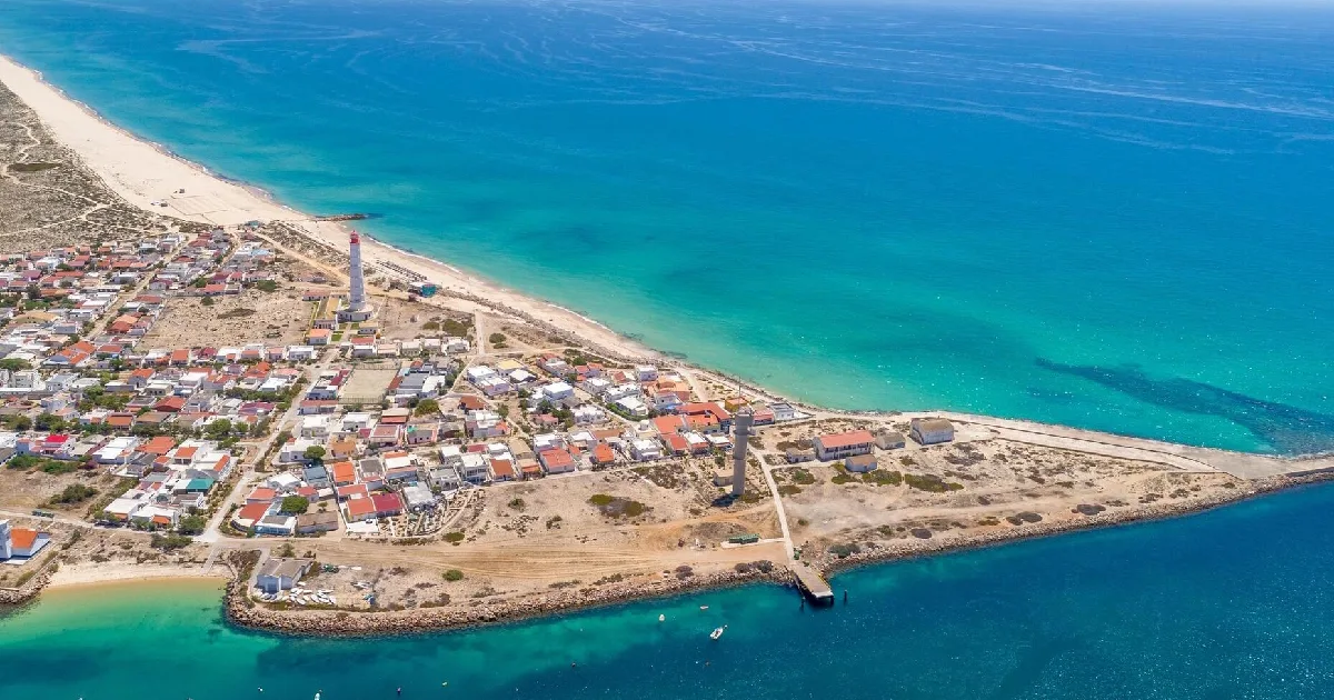 Vista aérea de vilarejo litoral com farol.