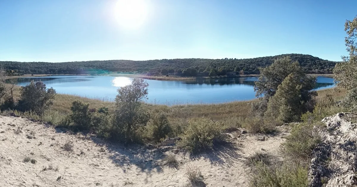 Paisagem natural com lago e sol brilhante.