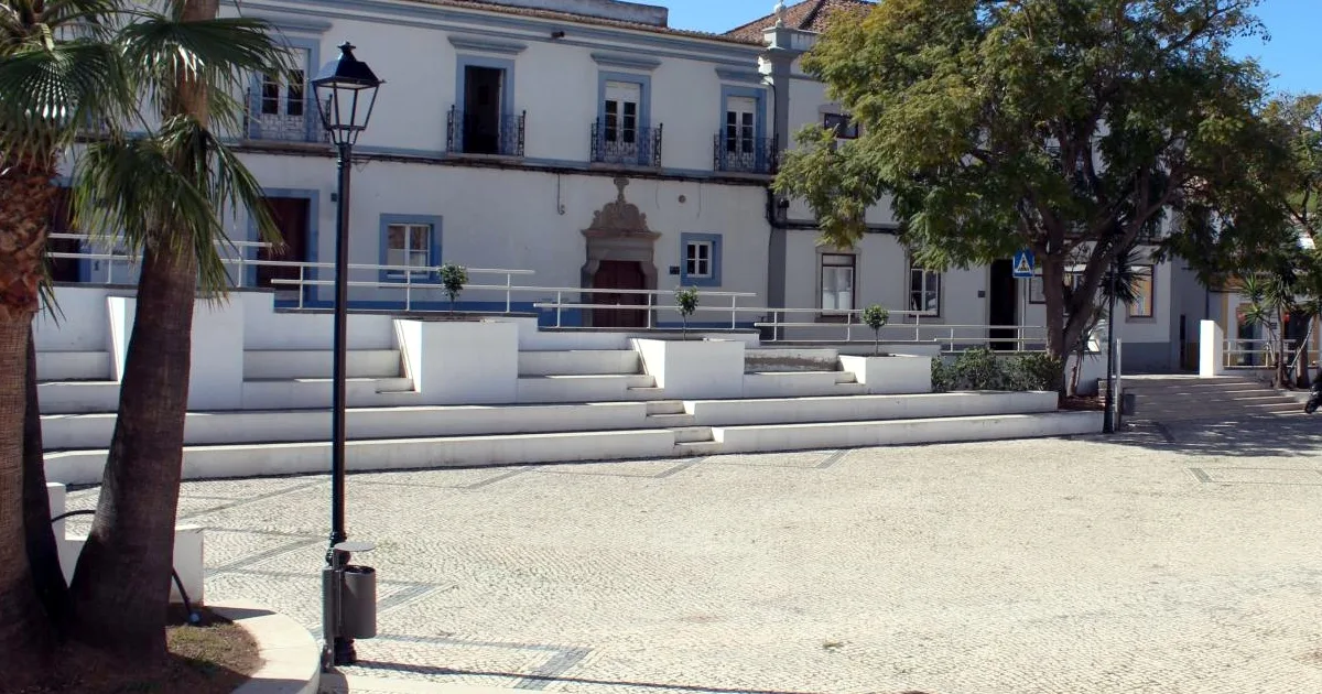 Praça calma com edifícios históricos e candeeiro urbano.