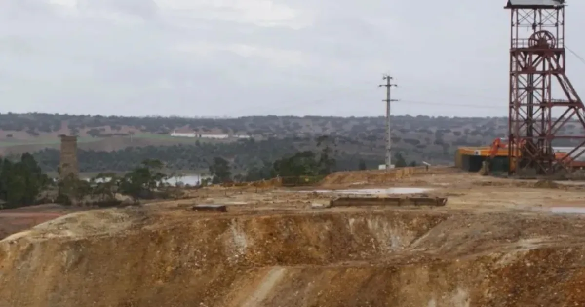 Mina desativada e paisagem rural ao fundo.