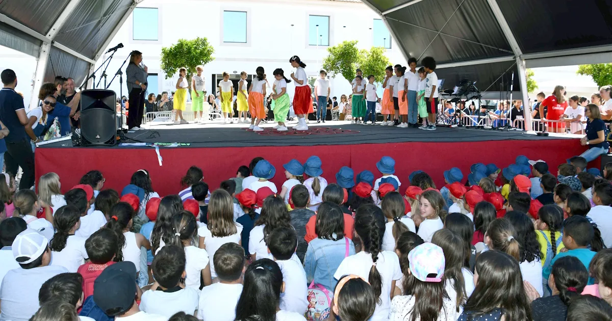 Crianças assistindo a apresentação escolar ao ar livre.