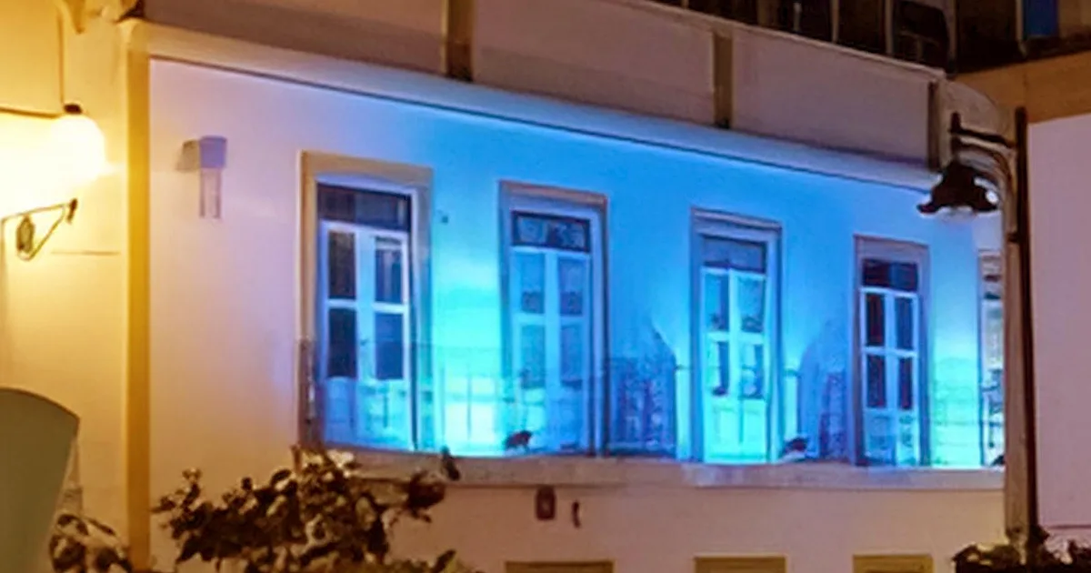 Fachada iluminada em azul à noite.