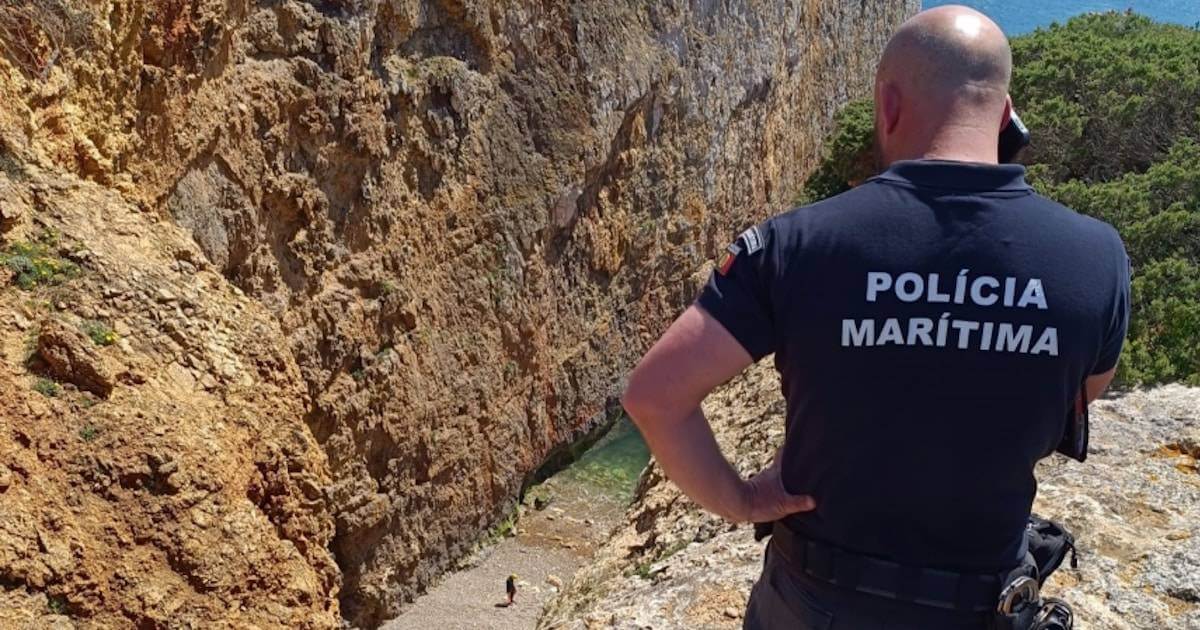 Agente da Polícia Marítima observando costa rochosa.