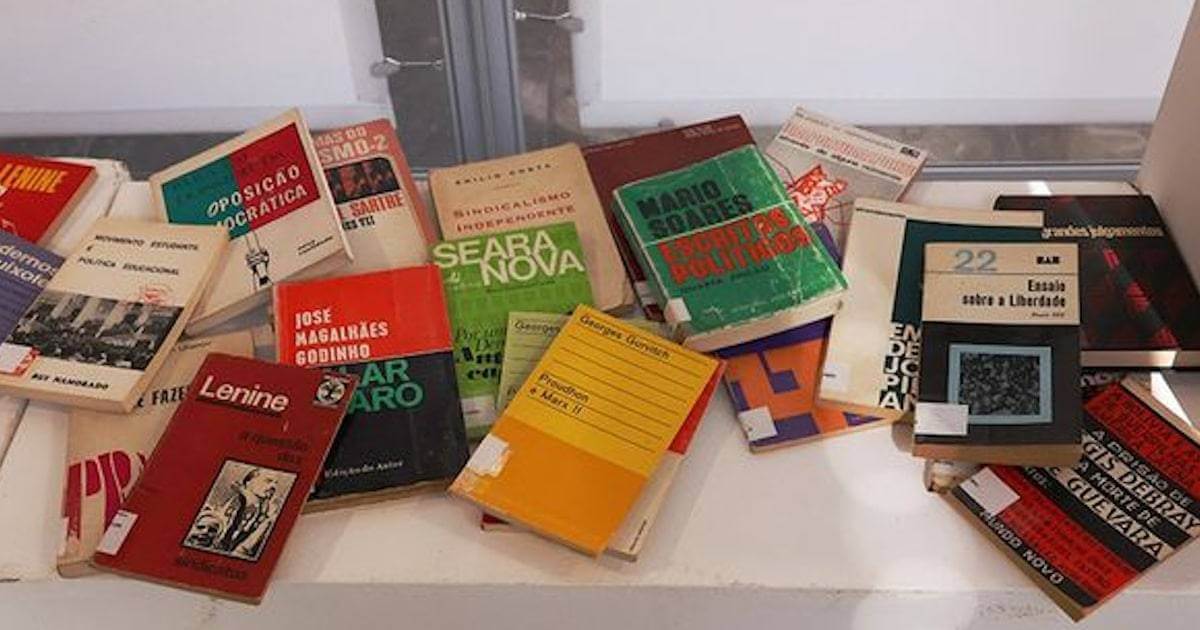 Livros antigos e políticos espalhados numa mesa.