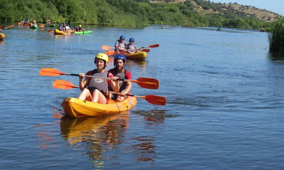 Pessoas praticando canoagem em rio ensolarado.