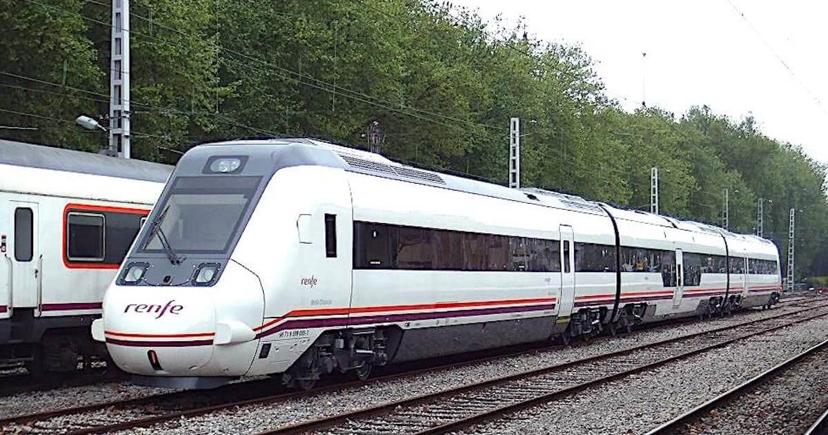 Comboio Renfe moderno em linha ferroviária arborizada.