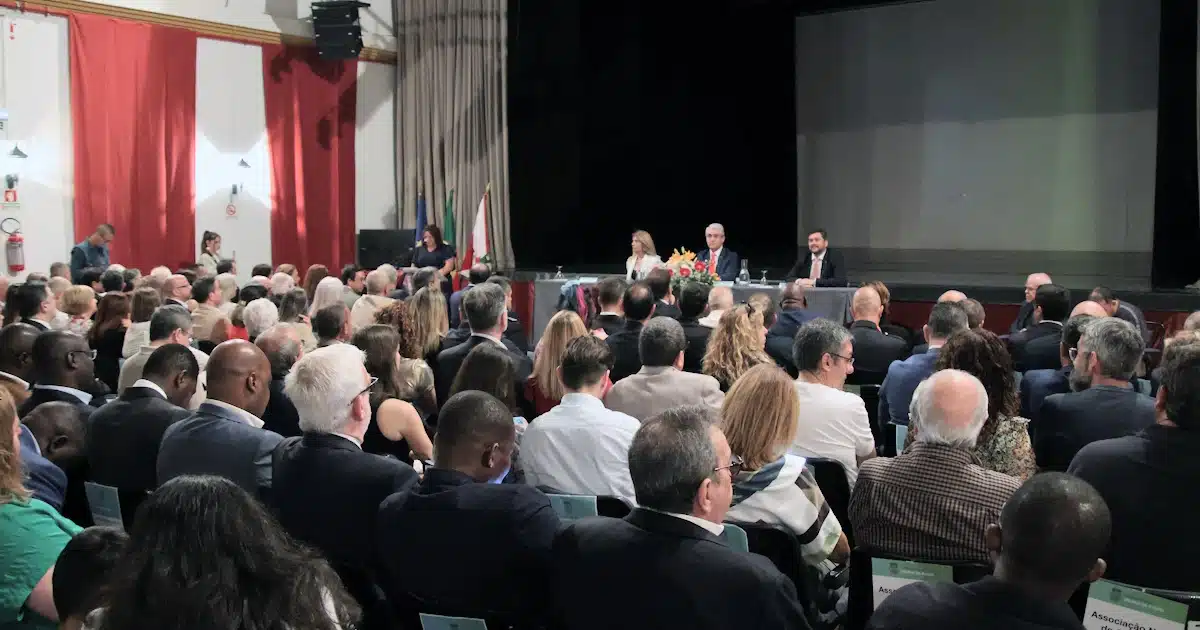 Conferência com público em auditório e painel ao fundo.