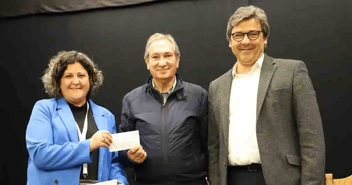 Três pessoas numa cerimónia de entrega de cheque.